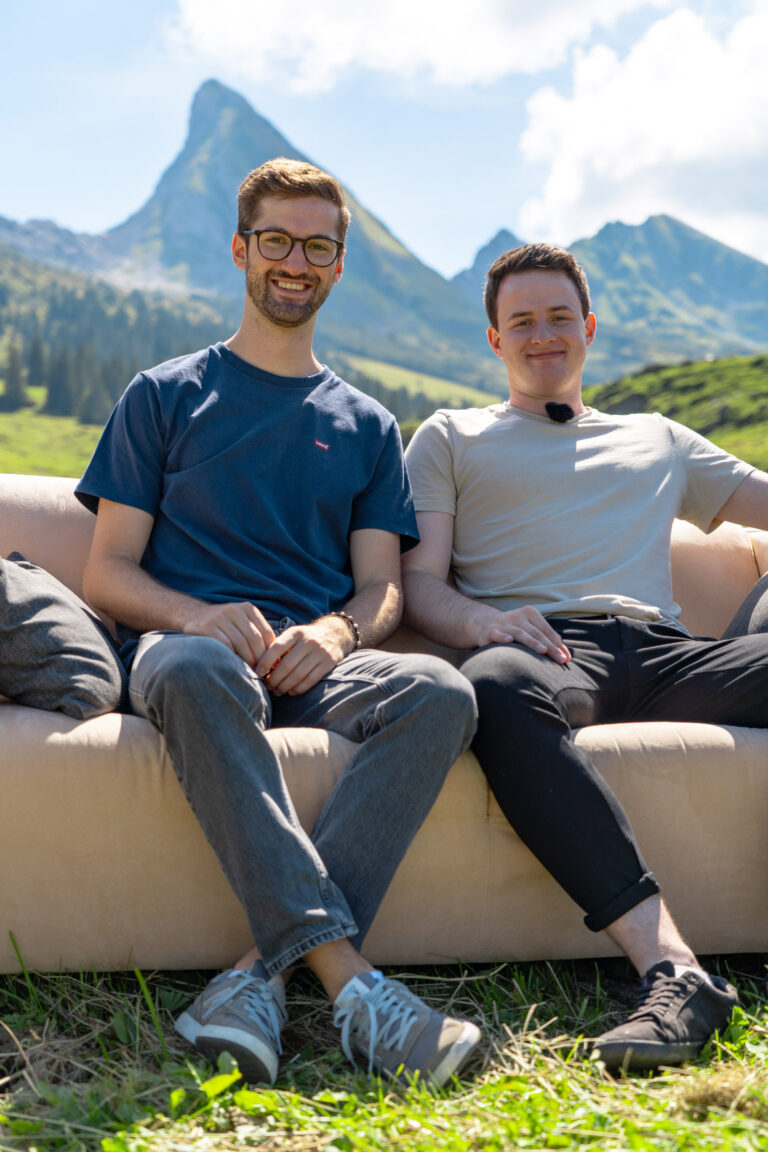 Manuel Lusti und Philipp Brügger sitzen auf einem Sofa vor den Churfirsten